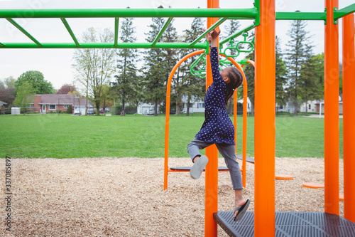 Young mixed child jumping onto the monkey bars at a playground photo