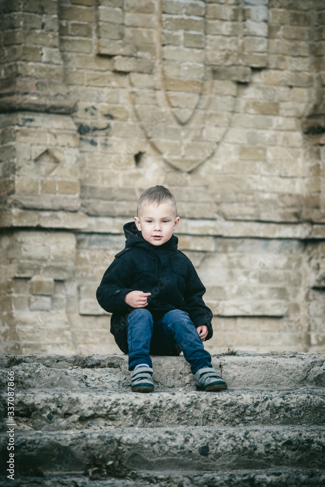 stylish boy in a coat on the background of an abandoned building stylish boy in a coat on the background of an abandoned building