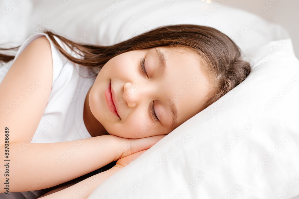 Little brunette girl sleeps sweetly in bed with white linen. space for text. healthy baby's sleep Little brunette girl sleeps sweetly in bed with white linen. space for text. healthy baby's sleep