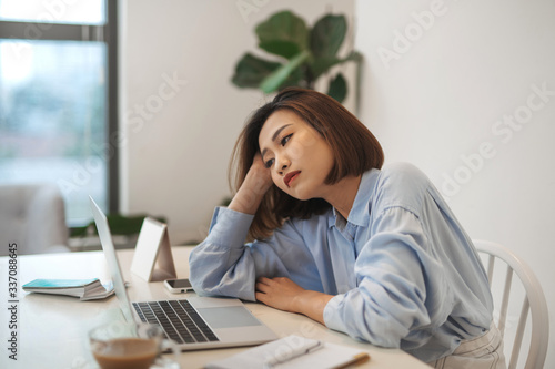 Bored millennial female worker lie at office desk look at laptop screen think about problem solution photo