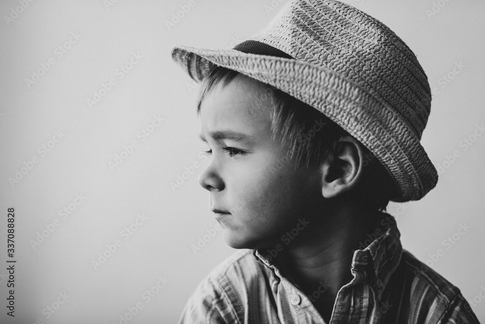profile of a pensive cute child in a straw hat. black and white image