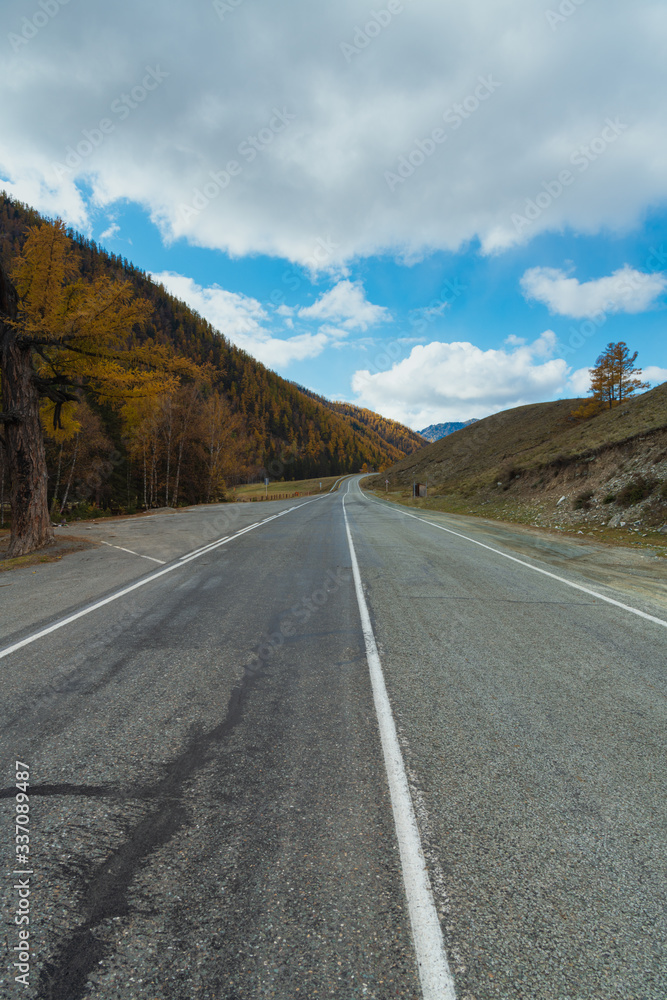 Road in the autumn mountains. Altai, Siberia, Russia. Yellow autumn forest and mountains with clouds. Road in the autumn mountains. Altai, Siberia, Russia. Yellow autumn forest and mountains with clouds.