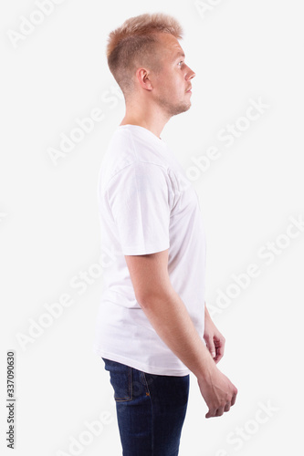 Caucasian man stands sideways to the camera and looks ahead. White background