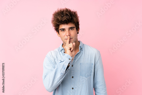 Young caucasian man with jean shirt over isolated pink background showing a sign of silence gesture putting finger in mouth