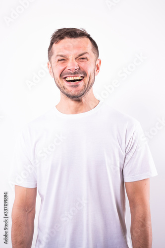 Attractive happy man smiles joyfully broadly. White background. Human emotions
