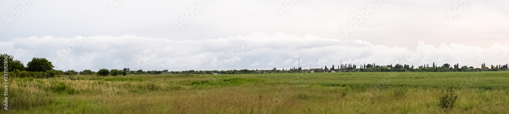 Cloudy landscape, village before the rain, visible large cumulus clouds and clouds over the village.