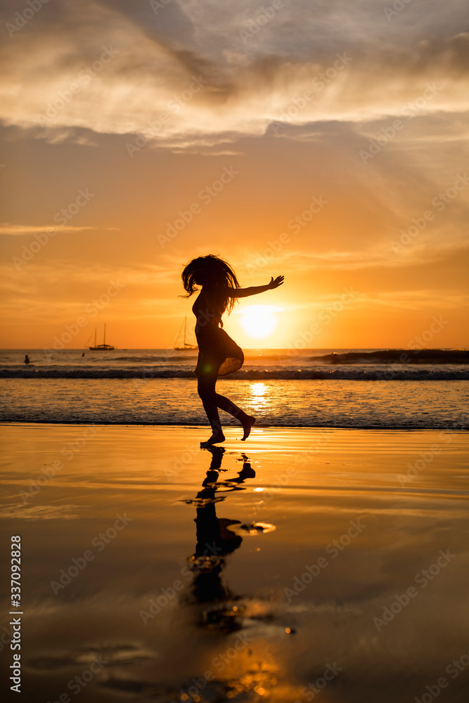 Woman walking on the beach during an amazing sunset Woman walking on the beach during an amazing sunset