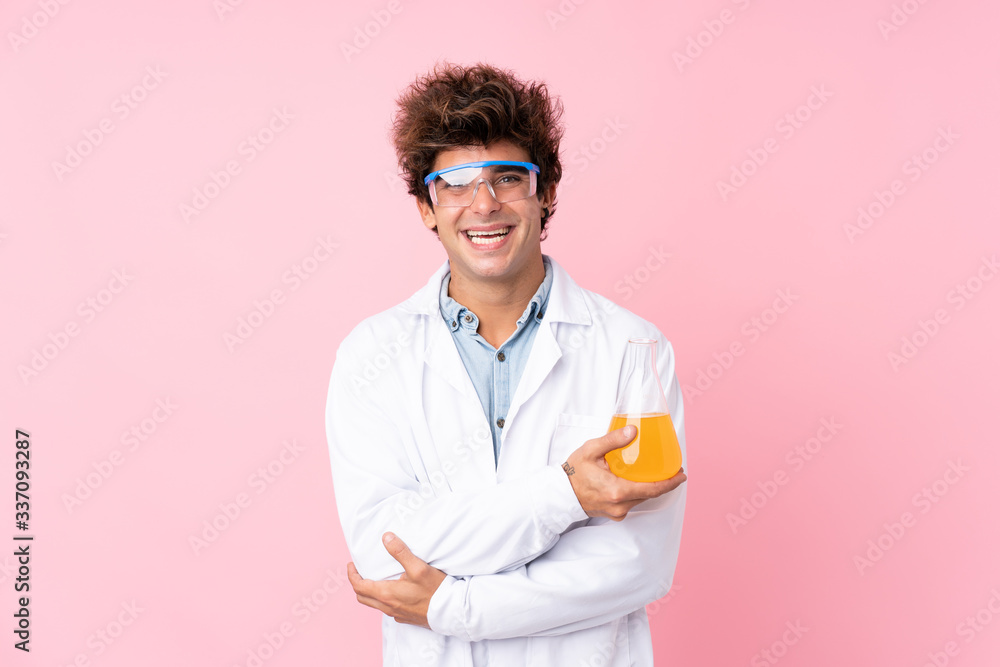 Young caucasian man over isolated pink background with a scientific test tube