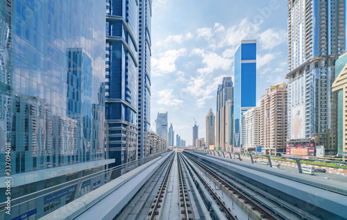 Canvas Print Train view on railway in Dubai Downtown at financial district, skyscraper buildings in urban city, UAE
