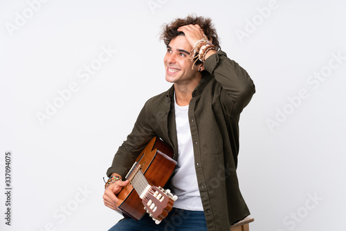 Young caucasian man with guitar over isolated white background laughing