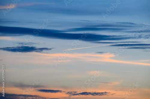 Contrail from airplane on a blue sky against a sunset.
