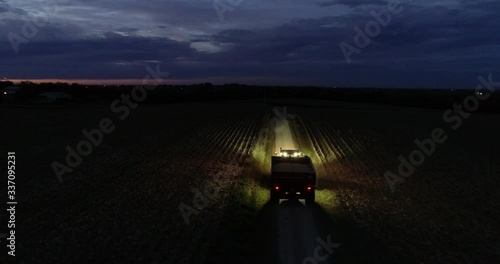 farmland machinery drives down dirt road at night, wide aerial
