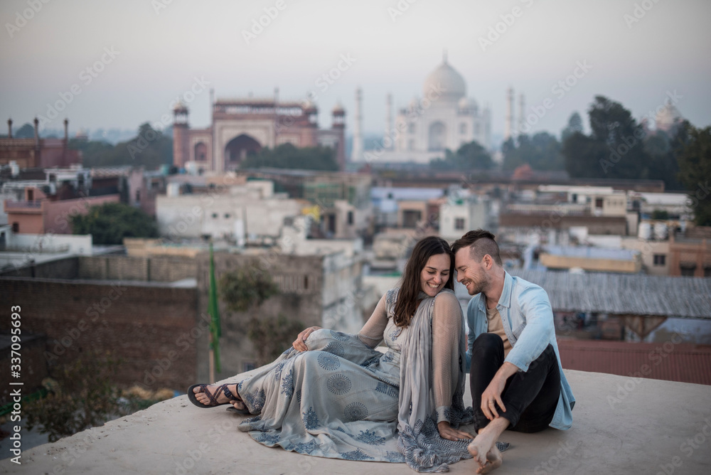 travel couple having picnic on rooftop in front of taj mahal in india