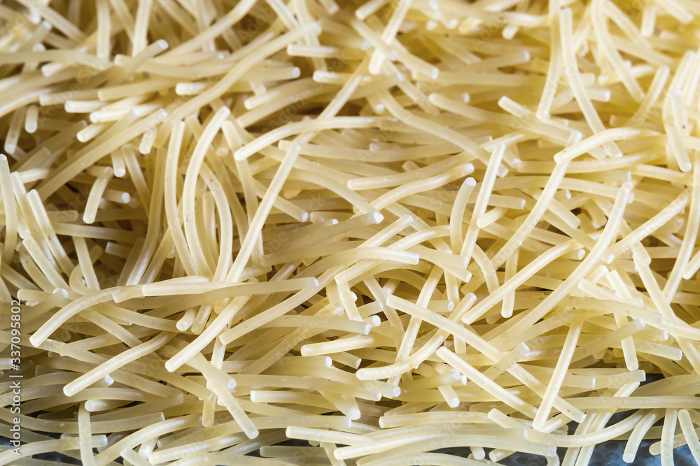 short thin vermicelli on the whole background. texture of dry yellow pasta.