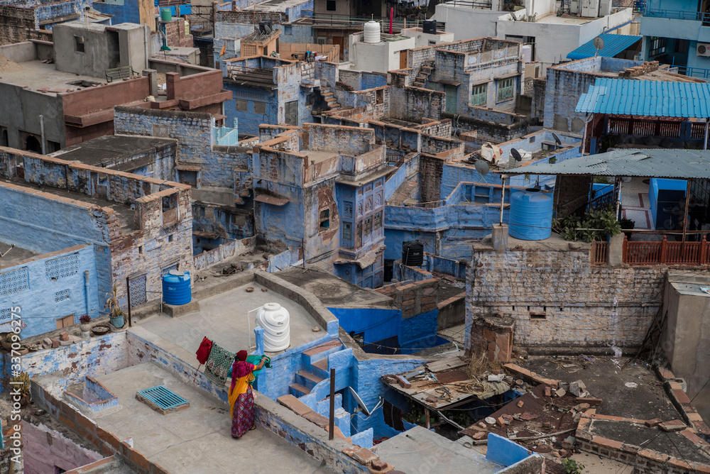 woman washing clothes on rooftop in blue city india