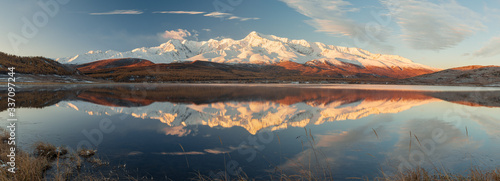 Wonderful sunrise landscape panorama of Kurai steppe with chuya river, mountain ice peaks of Siberia and sunny sky of Altai background. Natural scenery of autumn mountain forest. Altai, Siberia.