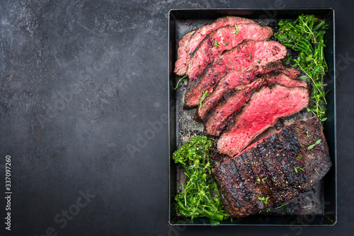 Traditional Commonwealth Sunday roast with sliced cold cuts roast beef with vegetable broccoli and salt as top view on a rustic metal tray with copy space left