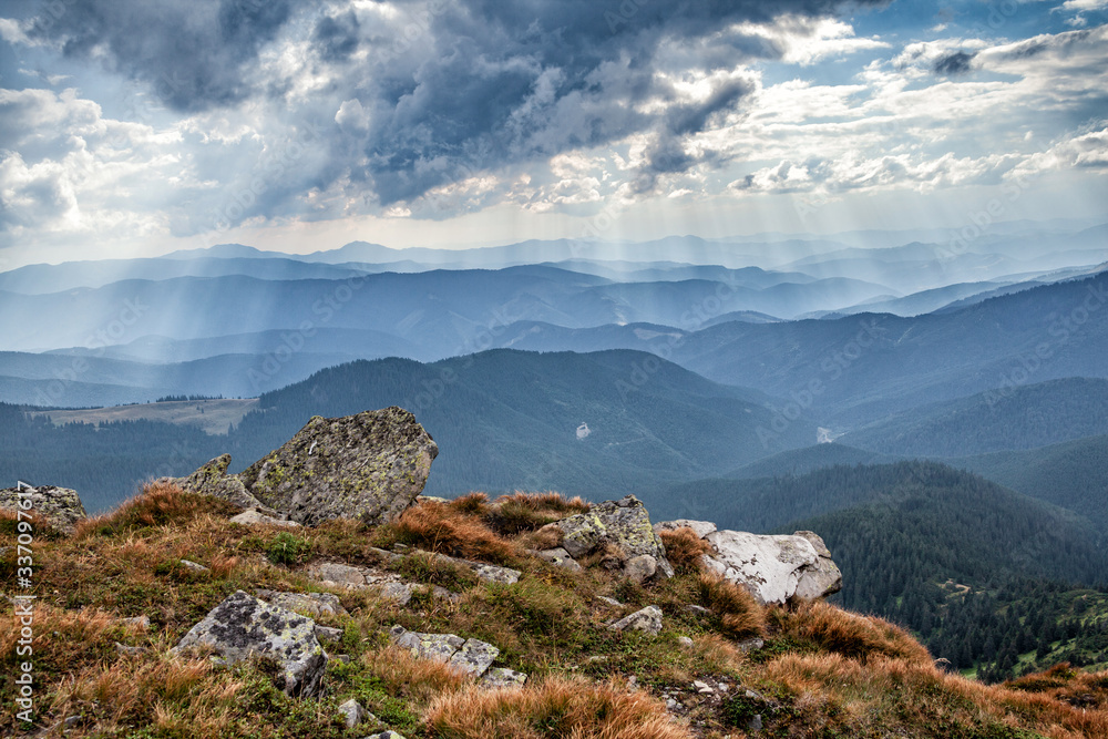 Fototapeta premium Panorama of mountain ridges silhouettes. Carpathians, Ukraine. Sun Rays Through Clouds. Summer mountain landscape.