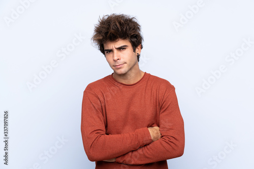 Young caucasian man over isolated blue background feeling upset
