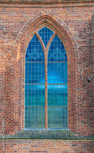 beautiful stained glass old blue window of cathedral in netherlands and bricks wall around