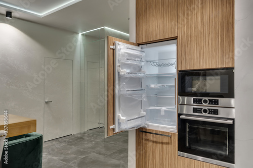 Multifunctional modern kitchen. Built-in appliances. Opened door of the new fridge photo