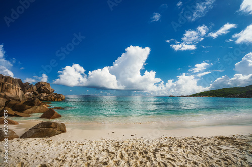 Grand Anse beach at La Digue island in Seychelles. Sandy beach with blue ocean and white clouds on sunny day