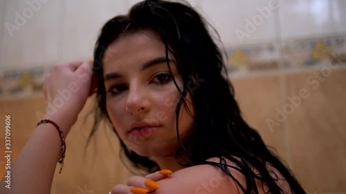 Young woman playing with wet hair, relaxing in bathroom, looking at camera photo