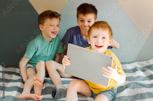 three boys play on a computer tablet and have fun