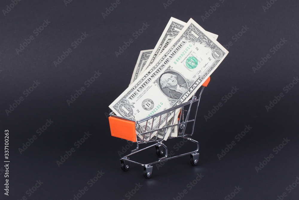 Shopping cart with dollars inside isolated on black Shopping cart with dollars inside isolated on black