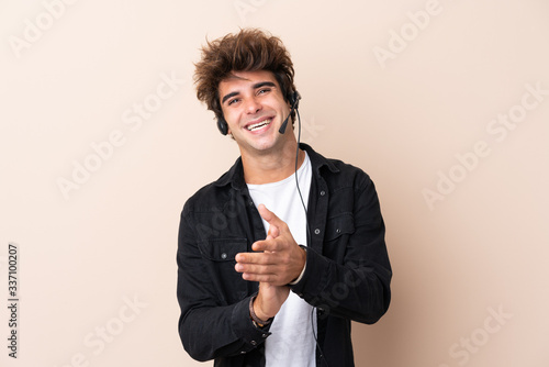 Telemarketer man working with a headset over isolated background applauding