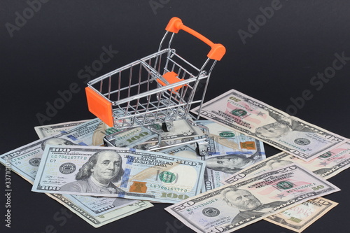Shopping cart with dollars inside isolated on black
