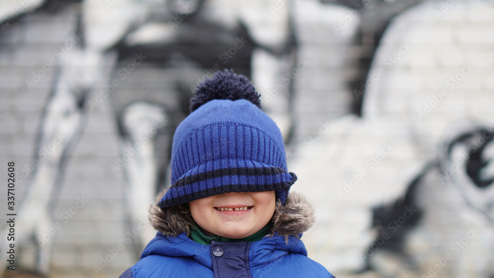Portrait of little funnyboy in a blue knitted hat stretched over the eyes Portrait of little funnyboy in a blue knitted hat stretched over the eyes