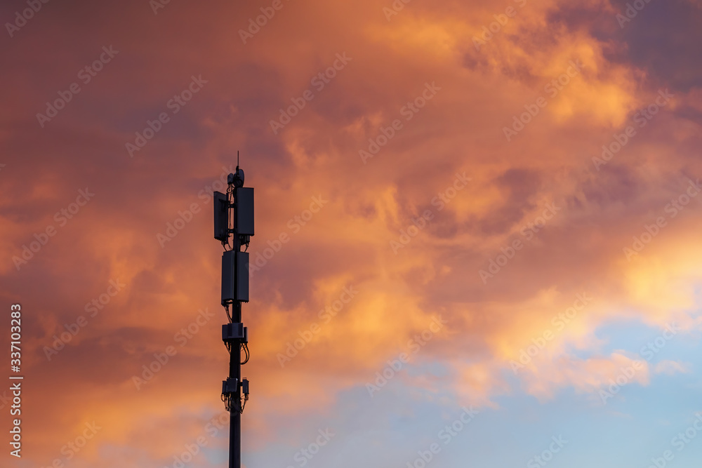 Cellular communications tower on beautiful dramatic clouds background in evening, copy space.