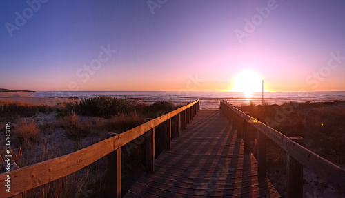 View of the atlantic ocean from a wooden jetty at sunset on a beach in Portugal