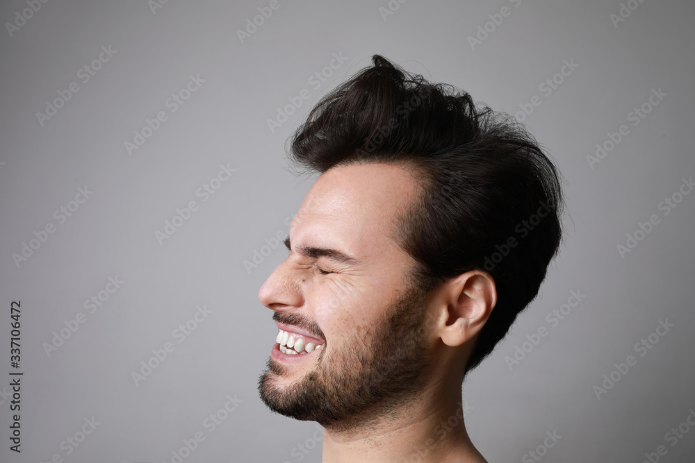 Close-up portrait of 30-year-old laughing man standing over grey background. Copy-space. Studio shot. Close-up portrait of 30-year-old laughing man standing over grey background. Copy-space. Studio shot.