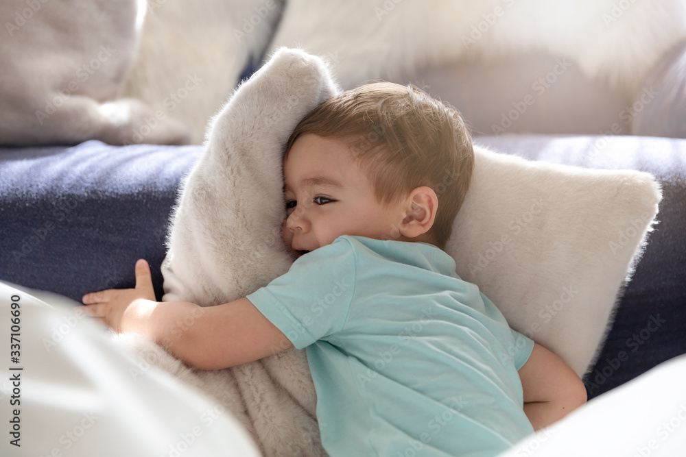 A little boy lying amid white fluffy cushions A little boy lying amid white fluffy cushions