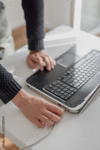 Man connects network lan cable to laptop with his hand. Close up shot, white background