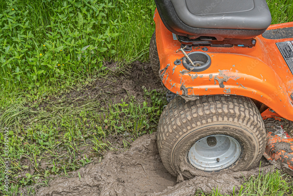 Obraz premium Dike, Texas, USA - April 9, 2020 - Lawn mower stuck in a muddy rut.