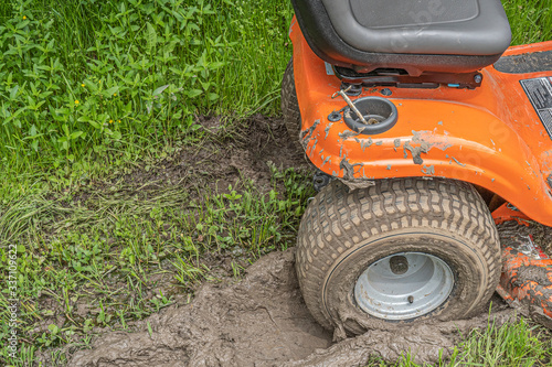 Dike, Texas, USA - April 9, 2020 - Lawn mower stuck in a muddy rut.
