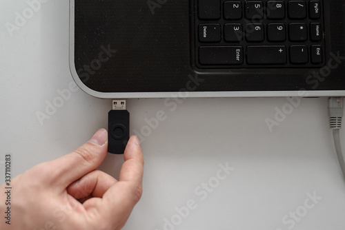 a man plugs a USB flash drive into a laptop with his hand