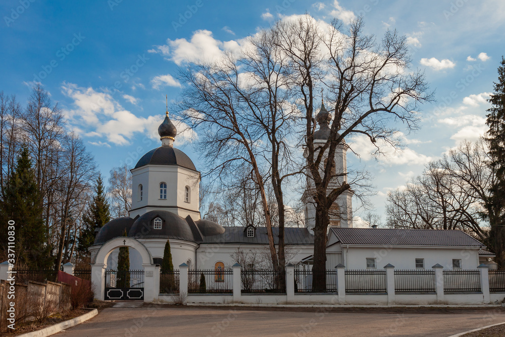 An Orthodox church surrounded by a stone fence with white walls and black domes