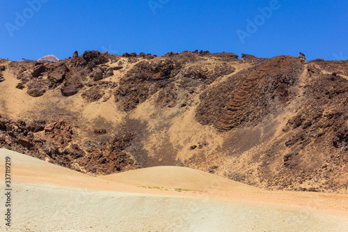 Volcanic landscape with Mount Teide on background. Moon like arid field on sunny day at famous park in Tenerife  Spain
