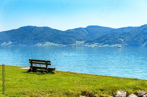 Beautiful view on Attersee lake im Salzkammergut alps mountains, bench, boats, sailboats, sailboat by in Nussdorf, Zell am Attersee. Upper Austria, nearby Salzburg. © Mikalai