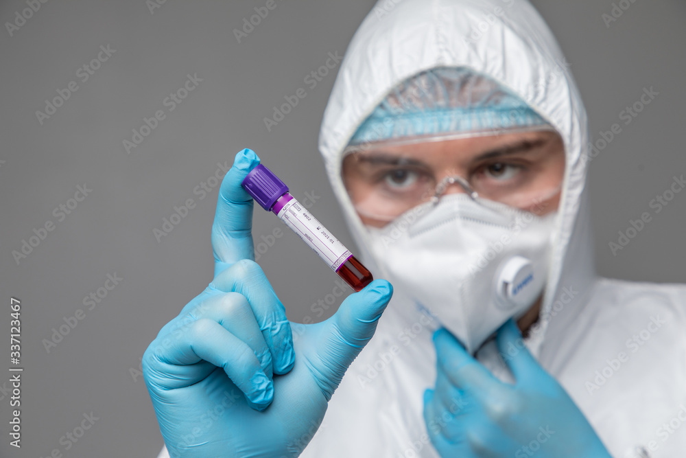 Man wearing HAZMAT protective clothing holding blood test tube filled with blood isolated on white background. Man wearing HAZMAT protective clothing holding blood test tube filled with blood isolated on white background.