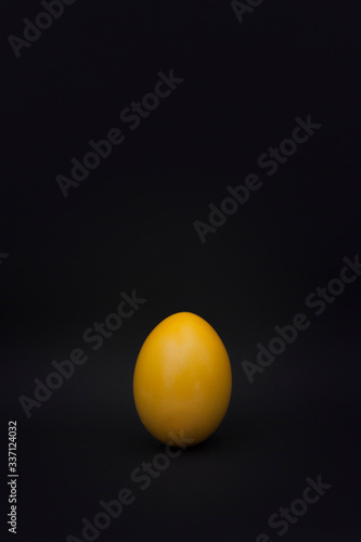 Gelbes Osterei vor schwarzem Hintergrund. Yellow easter egg on black background.