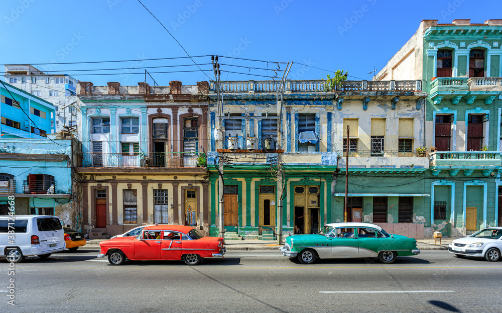 Havana Cuba Typical collection of old vintage colored houses in downton with american classic cars.