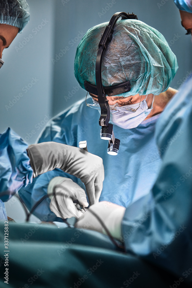 © Georgii - In the hospital operating room. An international team of professional surgeons and assistants works in a modern operating room. Professional doctors celebrate successfully saved lives. © Georgii - In the hospital operating room. An international team of professional surgeons and assistants works in a modern operating room. Professional doctors celebrate successfully saved lives.