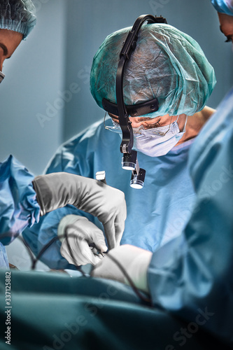 In the hospital operating room. An international team of professional surgeons and assistants works in a modern operating room. Professional doctors celebrate successfully saved lives.