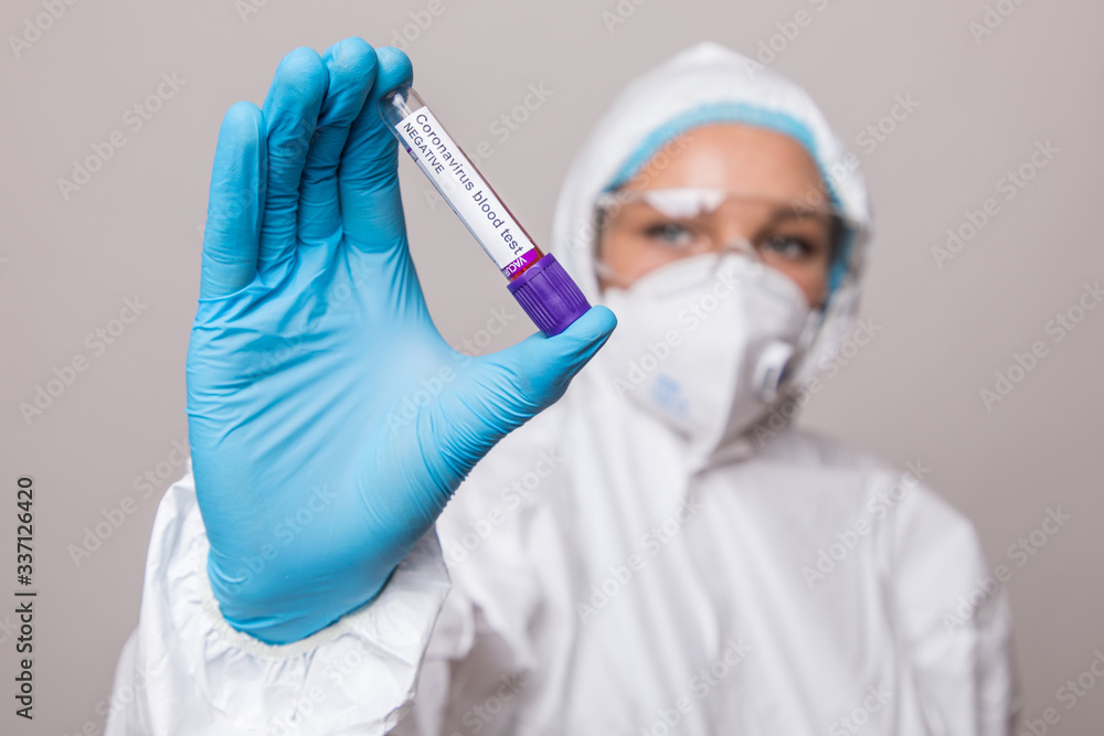 Female doctor or nurse in protective suit and face shield holding negative blood test result for coronavirus or covid-19. Female doctor or nurse in protective suit and face shield holding negative blood test result for coronavirus or covid-19.