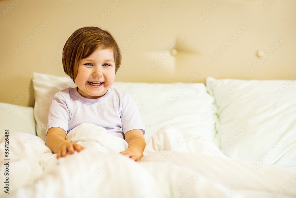 a sweet little girl with blue eyes ,lying in a white bed, under quarantine because of the covid-19 pandemic a sweet little girl with blue eyes ,lying in a white bed, under quarantine because of the covid-19 pandemic